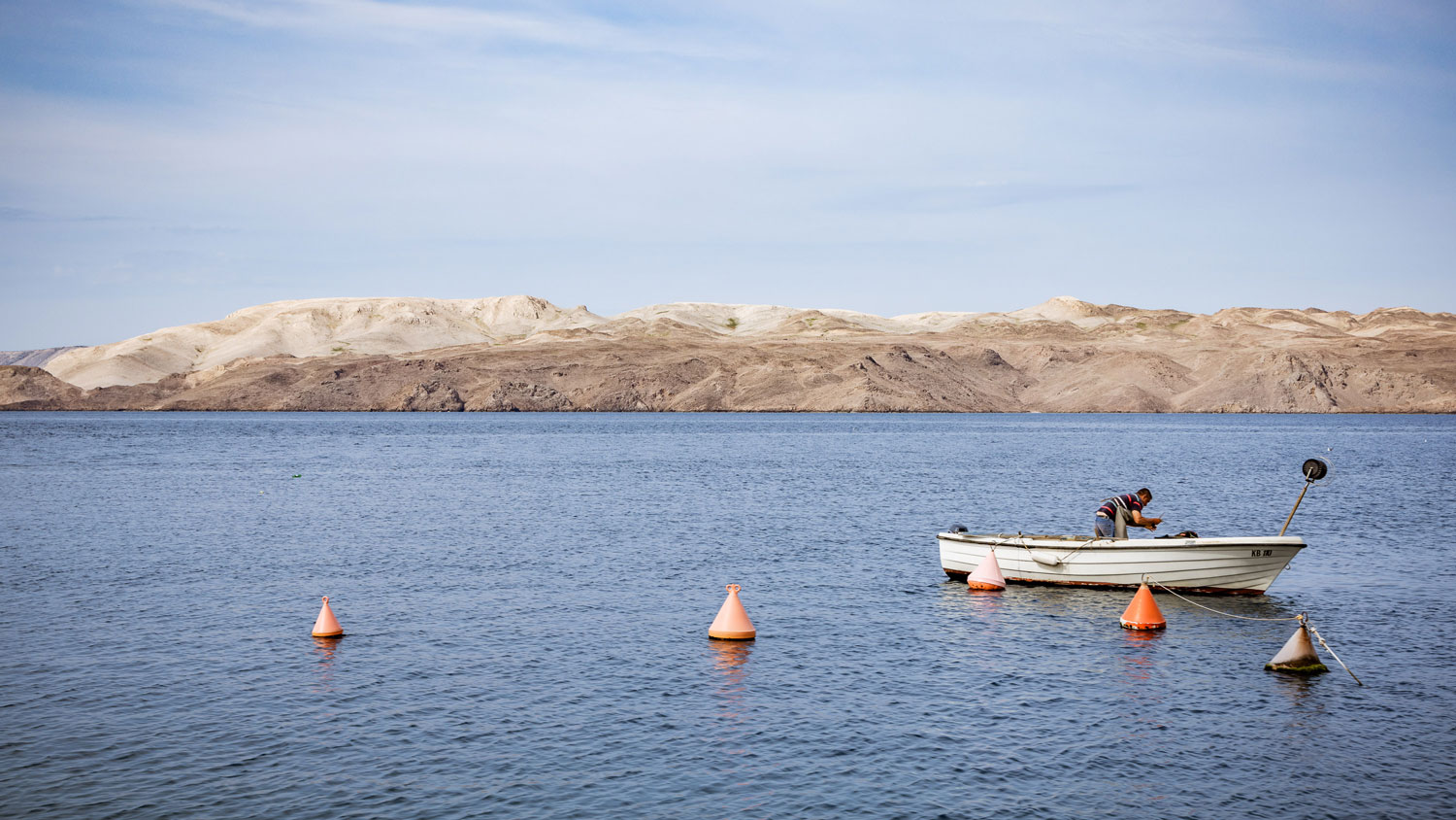 fischer im ruderboot vor karger insel